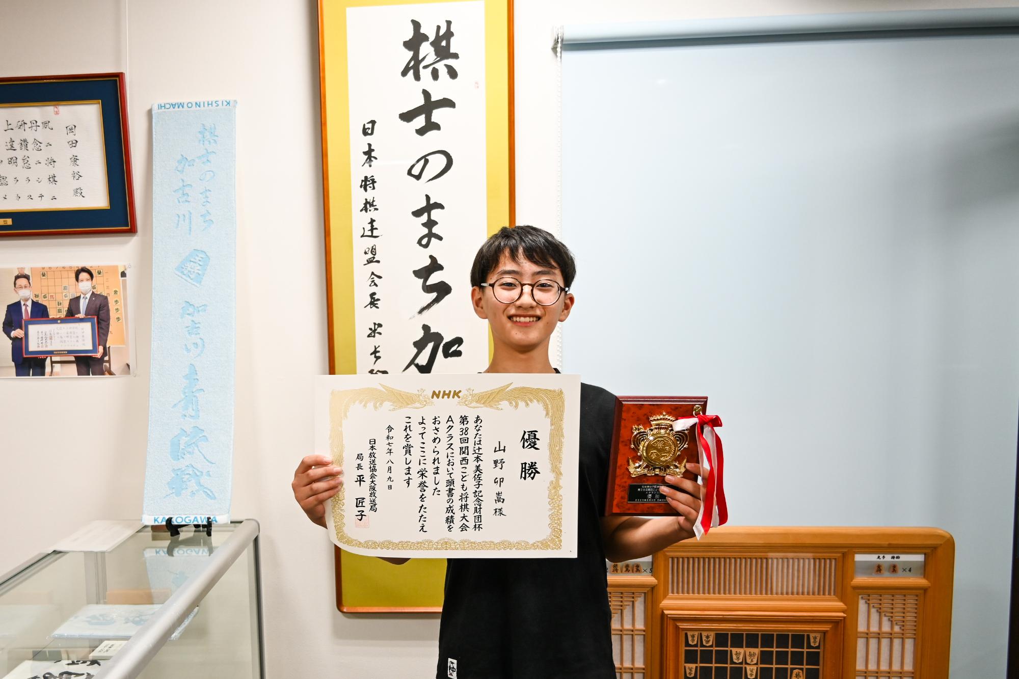 将棋プラザで賞状と盾を見せる山野さん