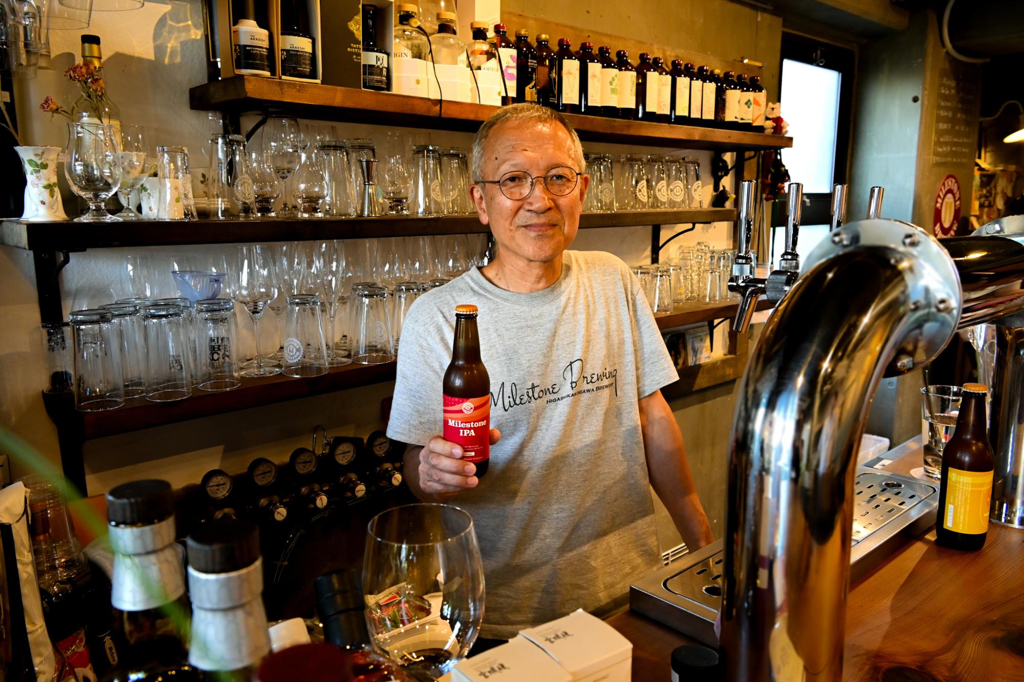作ったクラフトビールを持ちほほえむ大西さん