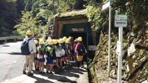 看板の掲げられたあけのべ鉱山入口に入っていく児童たちの写真