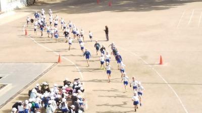運動場で一生懸命走る児童たちの写真