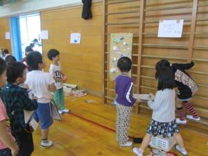 壁に取り付けられた手作りのおもちゃで遊ぶ児童たちの写真