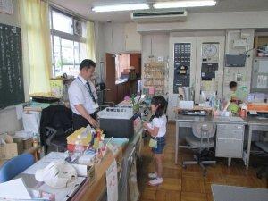 室内で教頭先生と名刺交換をしている1名の児童の様子の写真