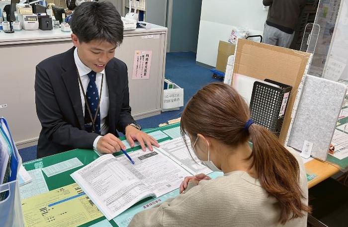 窓口で入園手続きを説明しているこども部幼児保育課の城島さんの写真