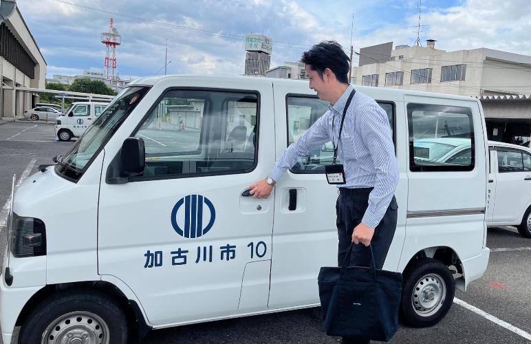 家庭訪問するために公用車へ乗り込もうとするこども部家庭支援課の石井さんの写真