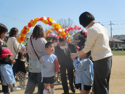 アーチをくぐって見送られる年長児
