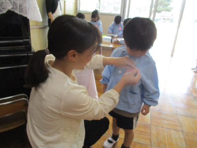 新しいクラスの名札をつけてもらう年中児
