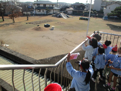 テラスから園庭をのぞく園児