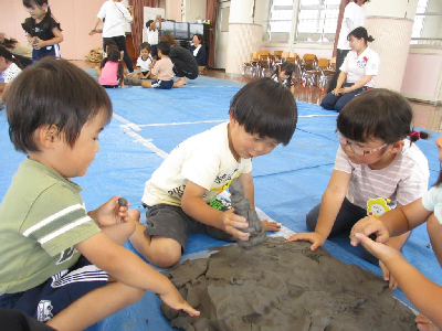 粘土に触れる年中児と年少児