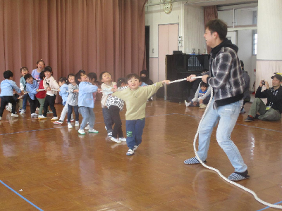 お父さんと一緒に綱引きをする年少児