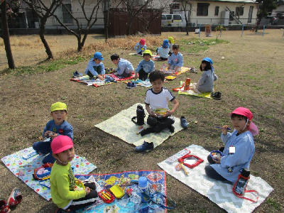 園庭でお弁当を食べる園児