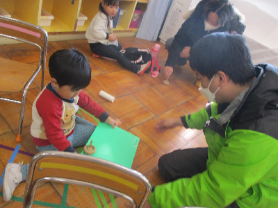 お父さんとこまをする園児