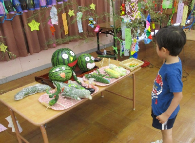 七夕のお供え物を見る園児