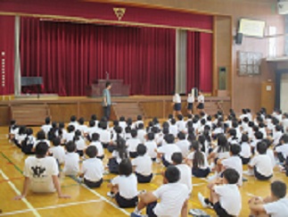6年生が4月のあいさつと最近のあいさつを実演し、どれだけ良くなったかを比較して伝えている。