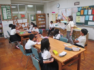 図書委員会の様子。担当教諭がこれまでの活動について尋ね、児童が挙手で応えている。