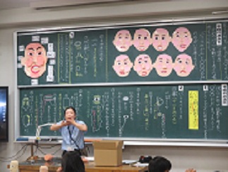 自分の顔を紙粘土で表現する活動の説明。作りたい表情によって粘土のつけ方が変わってくることを伝えている。
