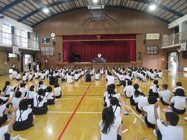 校長先生に夏休みのめあてを守れたかを尋ねられた児童が手を挙げている様子