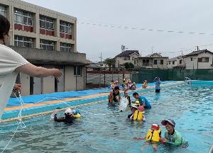 水難訓練でライフジャケットを着た幼児が保護者に助けを求めている