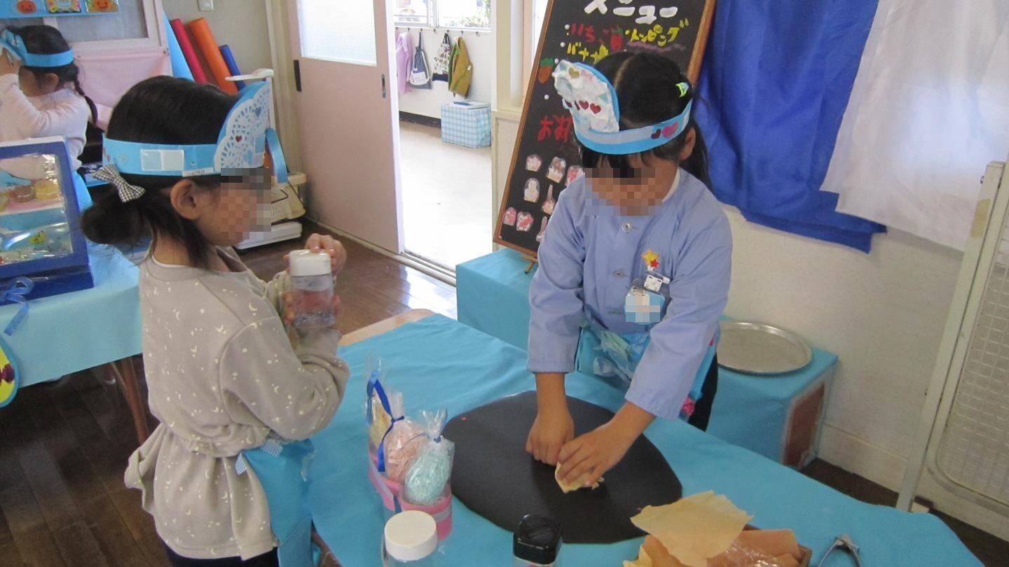 クレープ屋さんで作ったエプロンをつけてクレープを作る年長児。