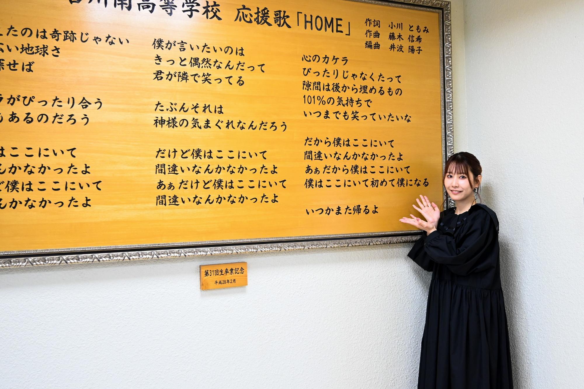 自身が作詞した加古川南高校応援歌歌詞の前で笑顔を見せるともみさん
