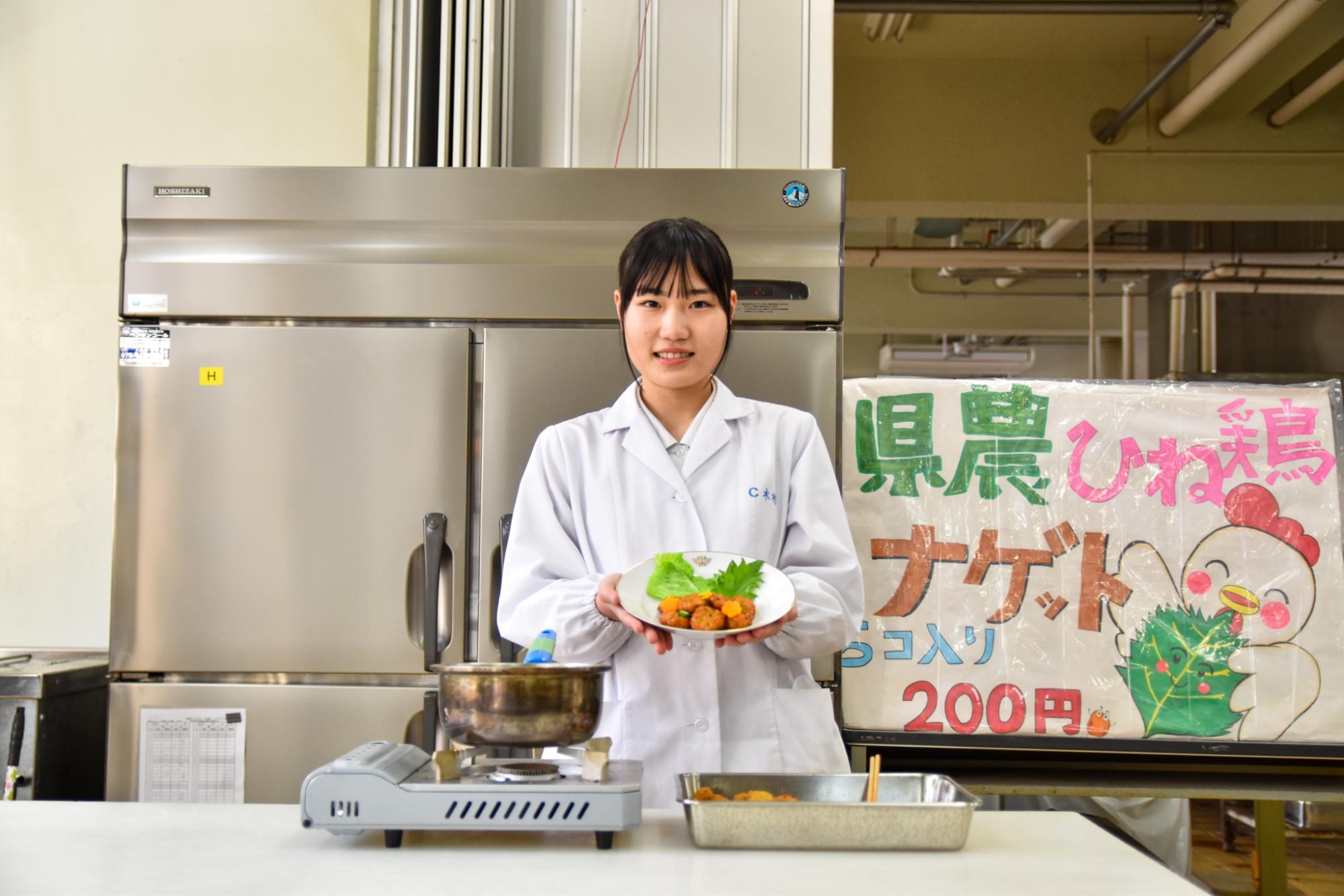コンテスト受賞のひね鶏の大葉ナゲットあんかけを持つ木村さん