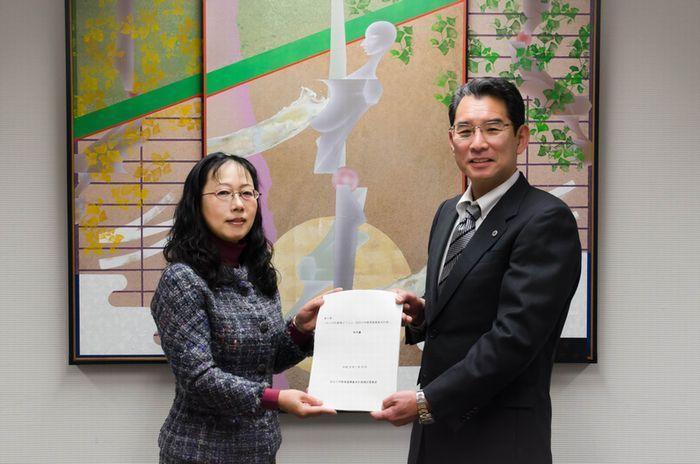 2人の男女が答申書を真ん中に持っている写真