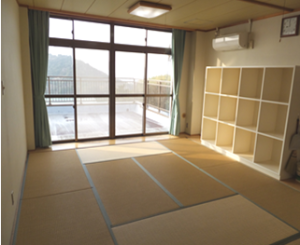 宿泊棟の畳敷きで窓にカーテンがついている10畳部屋の写真