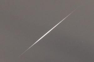 斜めに伸びて真ん中が太い細い線に見えるイリジウムフレアのアップの写真