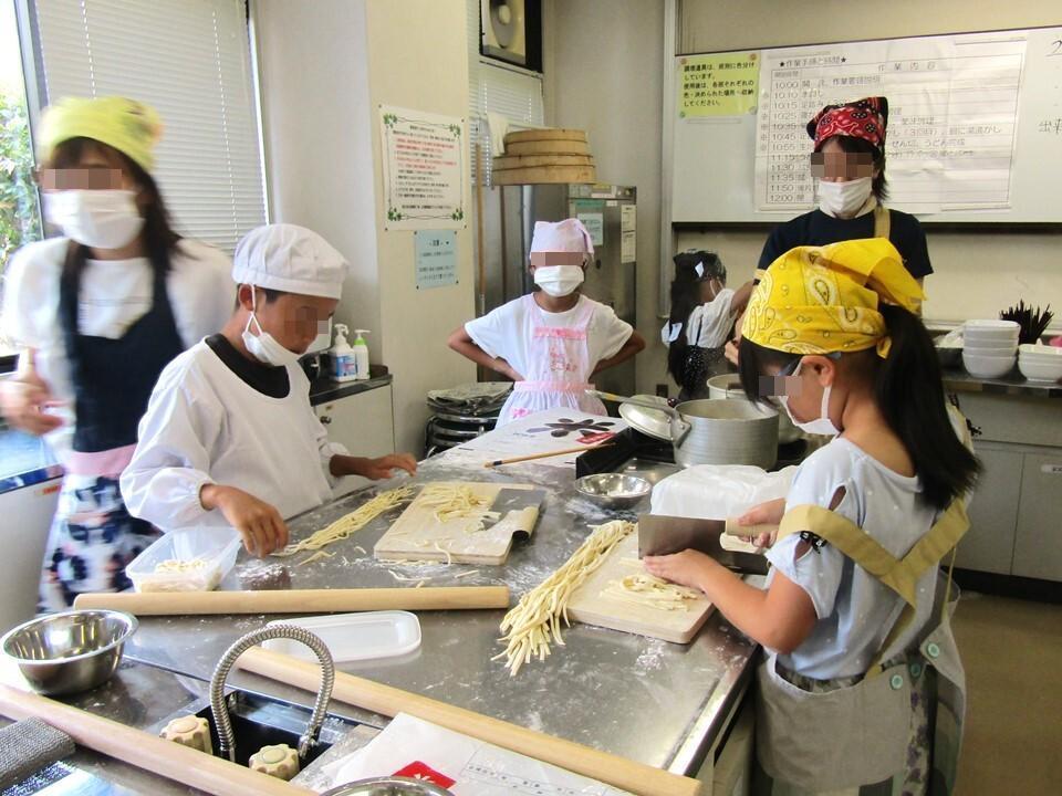 のばしたうどんの生地を折りたたみ、専用の包丁で細く切っている様子