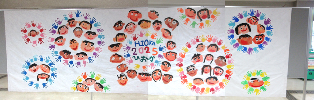 氷丘幼稚園とと氷丘南幼稚園児による、顔の絵とカラフル手のひらの押型です