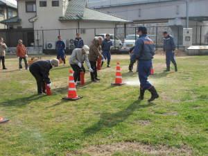 芝生の上で消火器の使い方を訓練する住民たちの写真