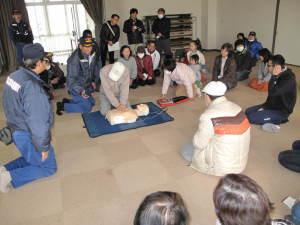 救急講習で心臓マッサージの練習を行っている住民たちの写真