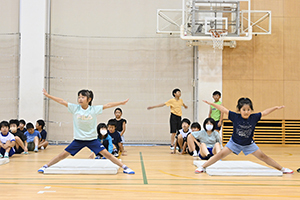 前転した後、手足を広げてポーズをとる子どもたち