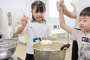 団子を湯から上げる女の子