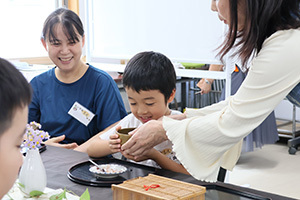 抹茶の飲み方を先生に教わる男の子