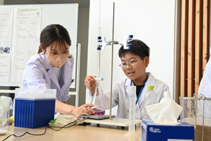 フラスコに薬剤を加える男の子