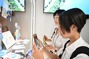 加古川市から駆け付けた女の子が展示ケースのかこのちゃんグッズの写真を撮る様子