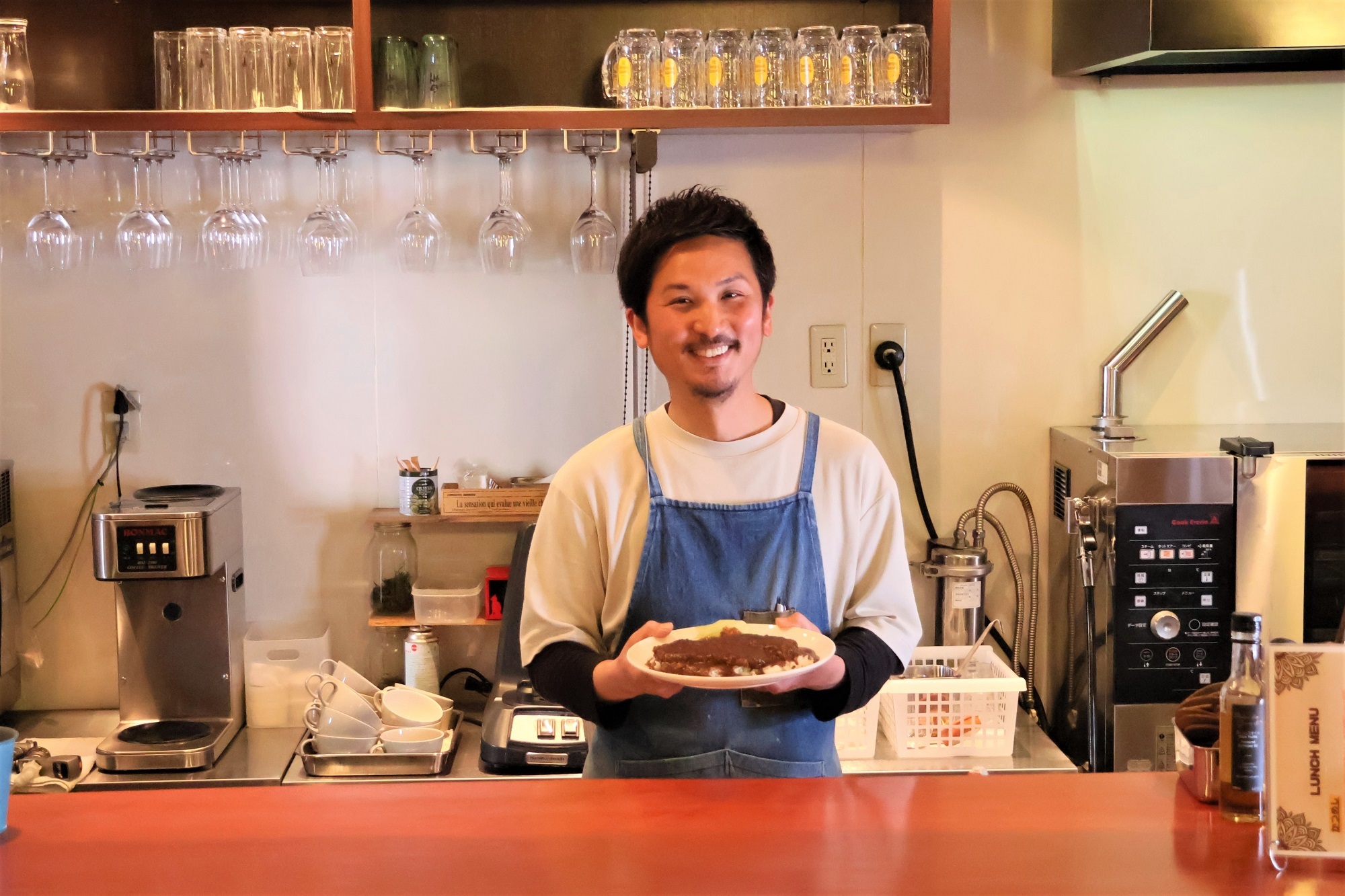 自慢のかつめしを手に微笑む一角さん