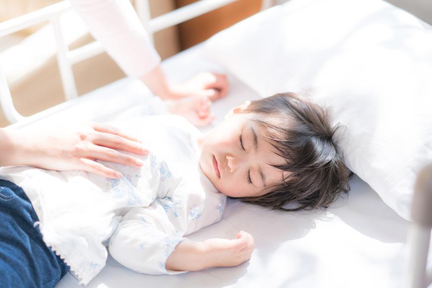 眠る男の子と母親の手の写真