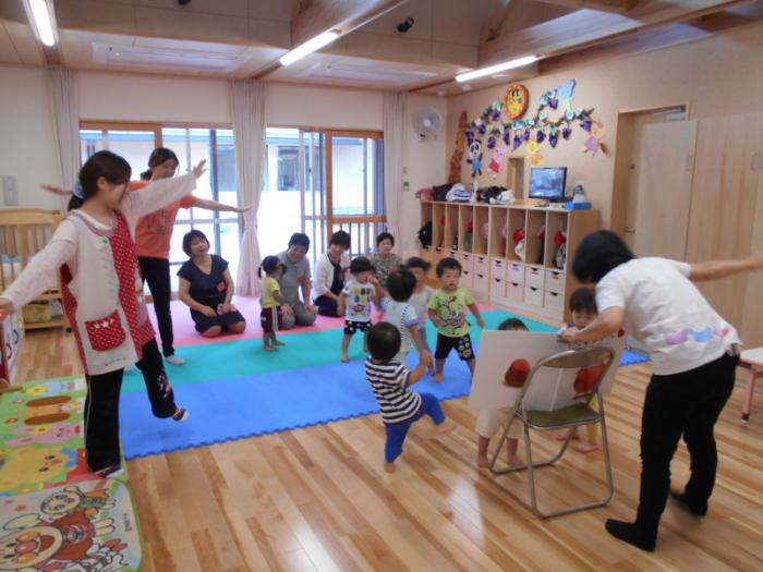 大型絵本の「だるまさんが」を見る園児たちの写真