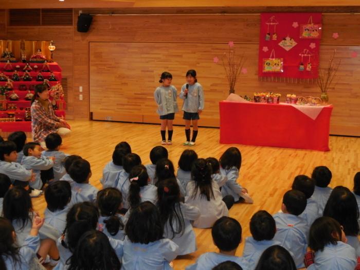 ひなまつり会でみんなの前に出て歌を歌っている女の子の園児2人の写真