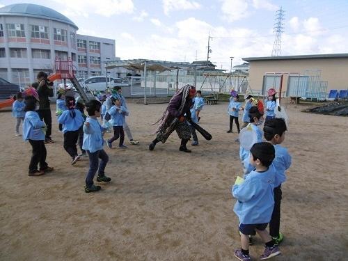 逃げ回る鬼に豆を投げる園児たちの写真