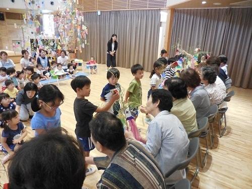 来てくださった老人クラブの皆様に笹飾りのプレゼントをする園児たちの写真