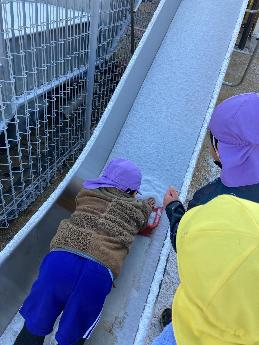 滑り台に積もった雪を集める5歳児