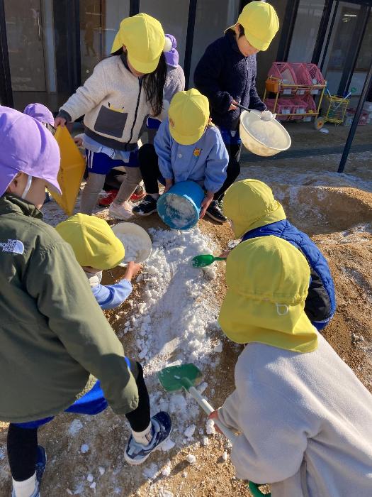 集めた雪でそり滑りをしようとする4歳児