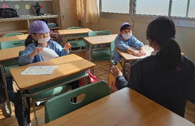 小学校の机に座って小学校体験をする5歳児