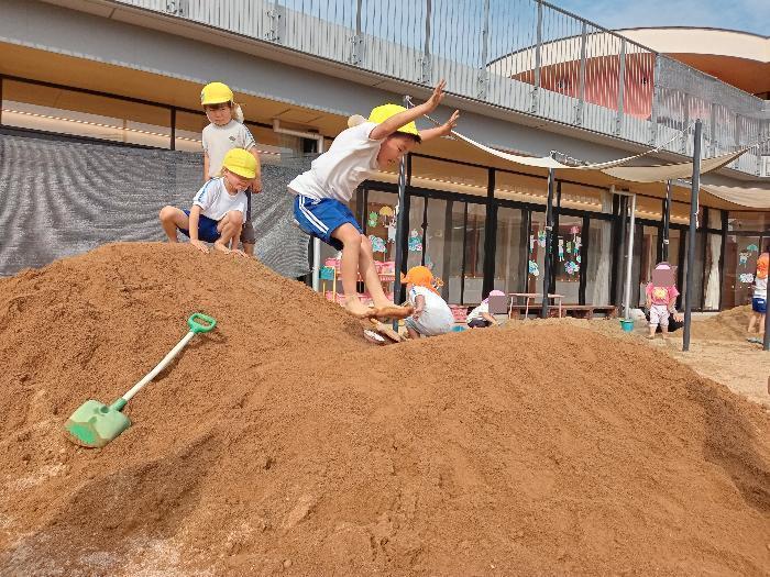 築山でジャンプする4歳児