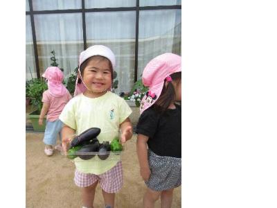 どっさりと実った野菜をもった2歳児