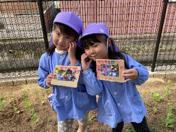 花を使った作品をもってポーズをきめる5歳児