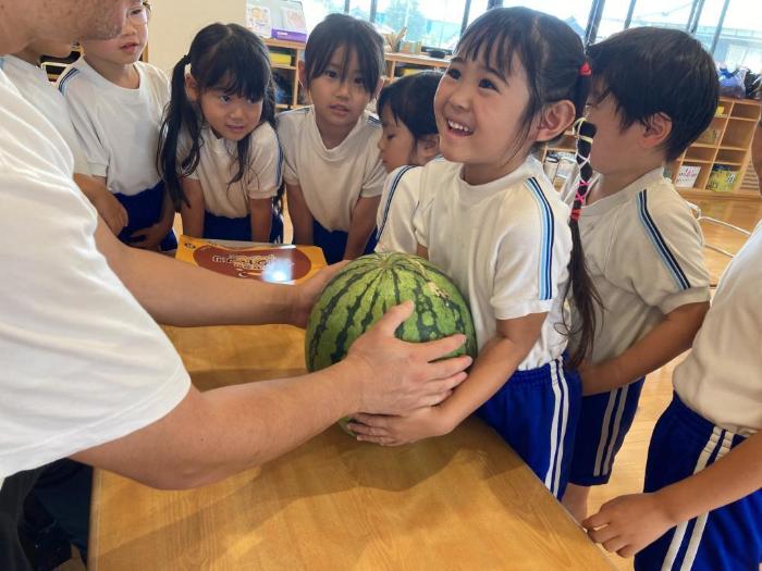 大きなスイカを驚いて抱きかかえる5歳児