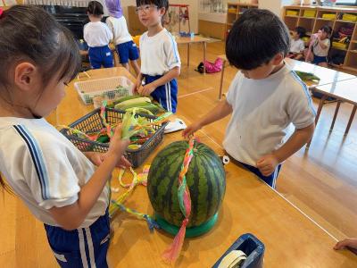 お供えのスイカに飾りを付ける5歳児